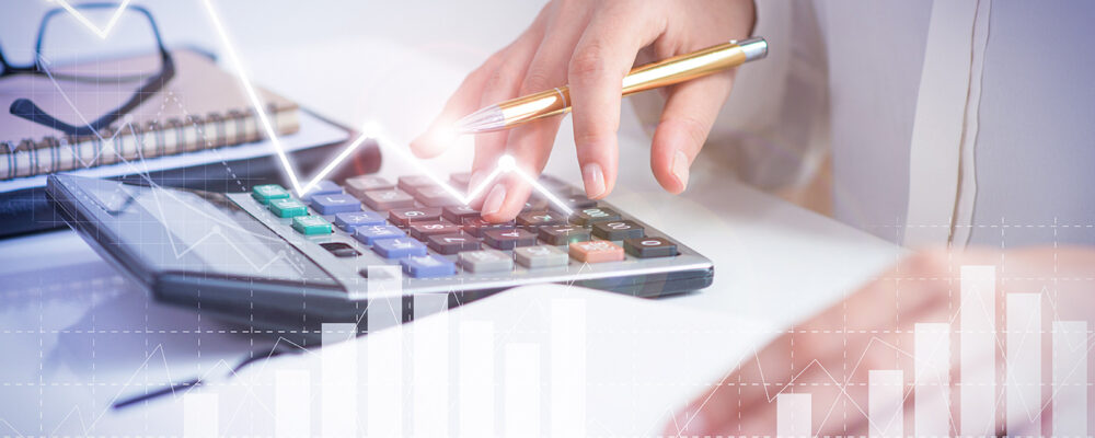Accountant calculating profit with financial analysis graphs. Notebook, glasses and calculator lying on desk. Accountancy concept. Cropped view.